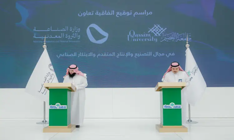 Two men wearing the Saudi Ghutrah, Eqal and Bisht at two microphone stands, signing the cooperation between the Ministry of Industry and Wealth and Qassim Mineral University. The selection of logos and banners of participating components, including advanced industrial production logos, is recommended.