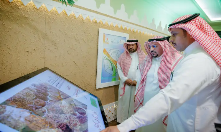 يقوم ثلاثة رجال بوجود البشتاء السعودي والغترة أو الشماغ والعقال باستخدام شاشة تفاعلية كبيرة تم رصد أنواع متعددة من الحبوب، وذلك وذلك ضمن فعاليات كرنفال بريدة للتمور. وقد تم في الخلفية ملصقات توعيه عن النخلة ورسومات بيانية موسوعة على الحائط، بما في ذلك الطابعة التعليمية والتنظيمية المقدَّمة من جامعة القصيم.