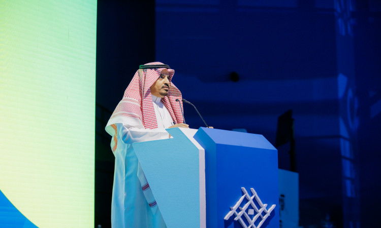 كاتب الجامعة كلمته في ختام النادي الصيفي، مرتديًا الغترة السعودية والعقال، وقد اكتمل مظهره الرسمي بالشت السعودي الفاخر. وقفة على منصة زرقاء أمام شاشة انتخابية ضخمة تزينها صفوف العمال والزرقاء، مقدمةً كلمته وسط جماهيرية جماهيرية مكانة جامعة القصيم واهتمامها بالأنشطة الطلابية.