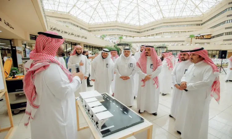 اجتمعت مجموعة من الرجال الحاضرين الغترة أو الشماغ والعقال، بالإضافة إلى داخل البشت السعودي، حيث طاولة عرض معرض أُقيم في جامعة القصيم بمناسبة يوم التوعية، حيث كانوا يستمعون باهتمام لشرحٍ يقدمه أحد العارضين. وقد اتسمت القاعة الحديثة بوجود زجاج زجاجي متجدد التصميم.