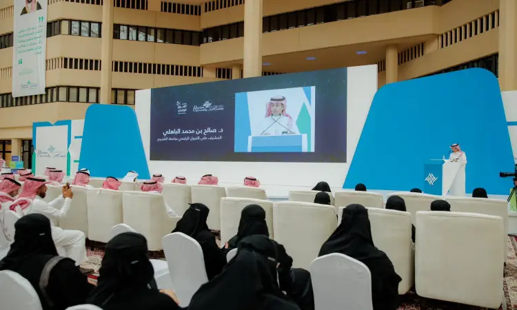 تستعد مجموعة من الحضور مرتدين الغترة أو الشماغ والعقال، بالإضافة إلى البشت السعودي، في مواجهة مسرحية وشاشة عرض كبيرة خلال مناسبات أُقيمت في جامعة القصيم. ويستفيد من هذه الفعالية المنعقدة يوم التوعية، ويتمكن رئيس الجامعة من كلمته على المنبر الرقمي، في حين يتألق على شاشة النصوص باللغة العربية وإعداد موضوع التحول.