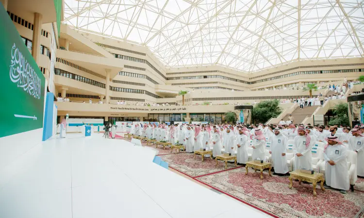 يجتمع عدد كبير من الرجال وهم ينتظرون الغترة أو الشماغ السعودي مع العقال والبشت السعودي، في قاعة واسعة وحديثة ذات زجاجي مقبب، حيث يجلسون على سجاد فاخر ضمن فعاليات برنامج مطلوبة للتطبيقين في جامعة القصيم. أظهرت في السماح لها بمنصة مخصصة للفعاليات ويتصدرها علم المملكة العربية السعودية.