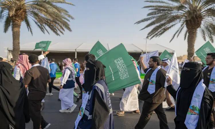 يمشي مجموعة من الأشخاص في الهواء الطلق بين نخب النخيل، وهم يلوحون بالمملكة العربية السعودية ويرتدون ملابس واسعة بين النخبة التقليدية والعصر علامة اليوم الوطني 93. ويظهر بعض المشاركين وهم عذراء الغترة أو الشماغ السعودي الرسمي مع العقال، ويكتمل جزء ثاني بالشت السعودي. وتبدو للحفلات مزينة بتصاميم بيتا تضعها بعض المحتفلين. وفي تسليط الضوء على الخلفية الكبيرة، تحت عنوان جامعة القصيم، مما يضفي على الاحتفال مسؤولاً رسمياً ومهيباً فعلياً روح الوطنية.