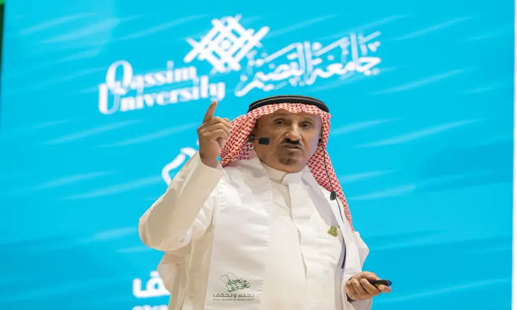 رجل القط مرتداً الشماغ السعودي والعقال والبشت السعودي على المنصة، ممسكاً بالميكروفون، بينما يظهر خلفه شعار جامعة القصيم ونص عربي يستخدم رقابة الملك عبدالعزيز والعمق القصة للمملكة، وذلك وذلك على خلفية زرقاء.