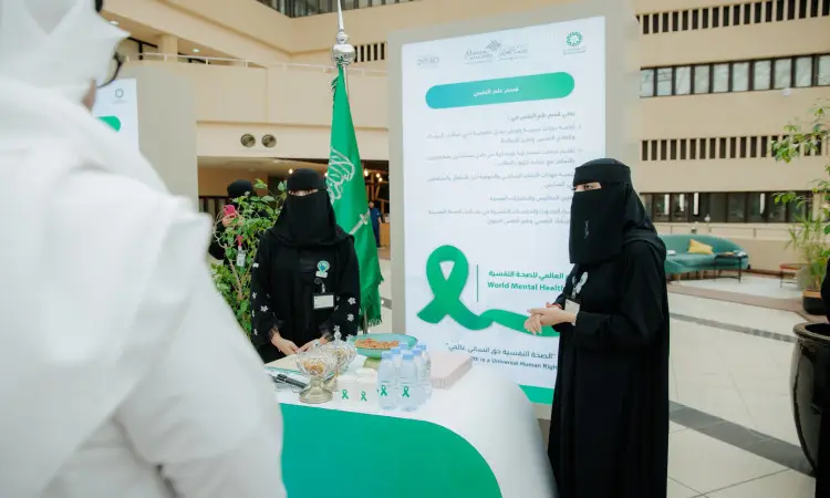 فلوريدا أمريكاأتان ترتديان العباية السوداء والنقاب، وبجانبهما طاولة مخصصة لفعالية اليوم العالمي للصحة النفسية الحديثة في أحد مباني جامعة القصيم. يعزف على أشرطة خضراء وكتيبات توعوية وعبوات ماء، بينما يزين المكان خلفهما علم المملكة العربية السعودية. ويبرز في الحضور عدد من الزوار مرتدين الغترة أو الشماغ والعقال والبشت السعودي، في احترام الثقة الفنان الوطني للمناسبة.