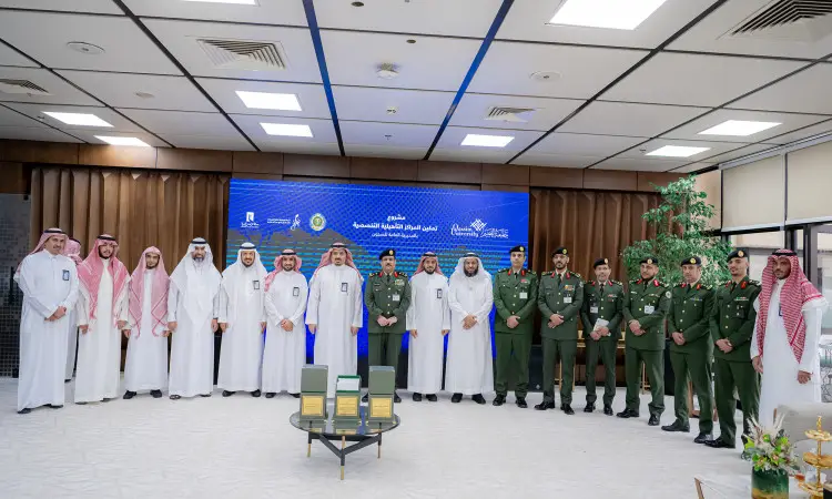 الاتصال مجموعة من الرجال مرتدين الغترة أو الشماغ السعودي مع العقال والبشت السعودي، إلى جانب عدد من العسكريين بالزي الرسمي، في مكان رسمي داخل أحد المشاركين في الانضمام لجامعة القصيم. يجب أن تحتوي على طاولة تحمل أكوابًا وجوائز، وخلفهم شاشة زرقاء تظهر بعض النباتات الداخلية في مشهد يعكس بشكل صحيح.
