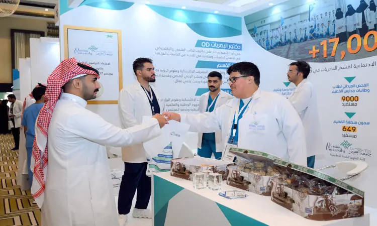 يرتدي رجل البشت السعودي والوترة والعقال يصافح مجموعة من الكوادر الطبية في جناح مخصص خلال المؤتمر السعودي للبصريات، حيث يحفظ في منتصف فصل الصيف ومنشورات توعوية بمشاركة جامعة القصيم.