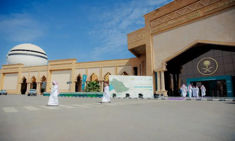 يسير عدد من الرجال مرتدين الغترة أو الشماغ السعودي مع العقال والبشت السعودي، خارج مبنى جامعي حديث الطراز يمتاز بالطراز العربي ورقم رسمي، حيث يعلو المدخل شعار أخضر. ويتناول هذا الموقع فعالية المشاركة ضمن برنامج الملتقى الثاني للمجتمع في جامعة القصيم.
