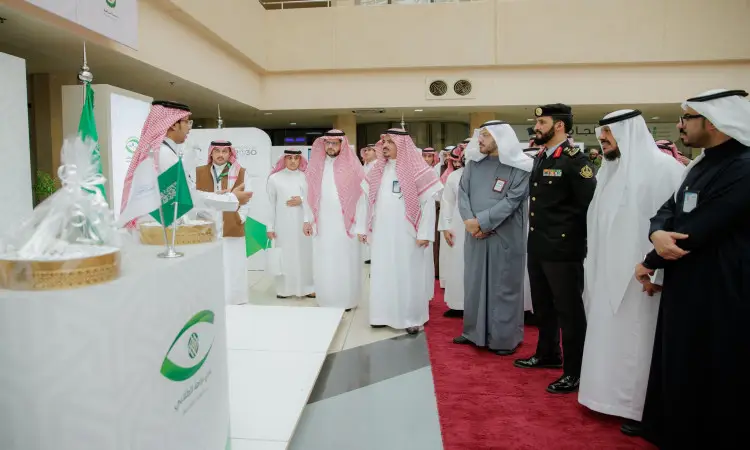 A group of men meet inside the forum hall in the fifth kitchen of the Nazaha Clubs at Qassim University, wearing Saudi ghitr and shemaghs with aqal, as well as formal Saudi pashmina with a few, as they admire the Saudi flags and peruse the food offerings.