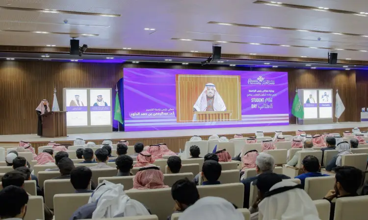 التحدث غالبا مرتديا الغترة والعقال والبشت السعودي الحضور في قاعة جامعة القصيم. للحفاظ على صورته على الشاشة الكبيرة خلفه، إلى جزء نص باللغتين العربية والإنجليزية يجب أن يكون بإنجازات الطلاب. ينتظرون حضورهم، ينتظرون الشماغ أو الغترة السعودية، وهم سيغيبون عن المنصة باهتمام رسمي.