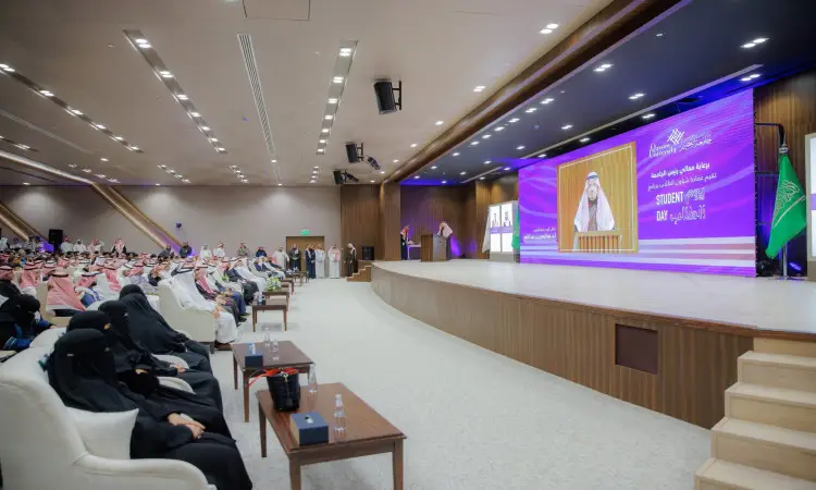 يجتمع جمهور كبير في قاعة محاضرات في القصيم، حيث يتابع الحضور منصة تتوسطها شاشة ضخمة لمواجهة الكبار، يحضرون الغترة السعودية والعقال والبشت السعودي الرسمي. ويقف إلى جانب جانب علم المملكة العربية السعودية، بينما يحضر الحضور رجالاً الشماغ أو الغترة مع العقال والبشت السعودي، إلى جانب سيداتٍ يشاركون في الاحتفاء بإنجازات الطلاب.