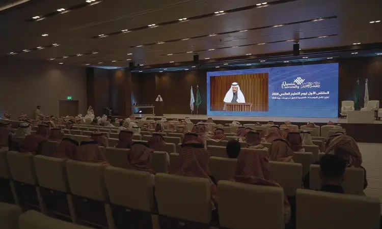 يجتمع عدد كبير من الحضور، مرتدين الشماغ السعودي والغترة السعودية مع المقالات والبشت السعودي التقليدي، في قاعة محاضرات. يتابع الجميع باهتمام رئيس الجامعة وهو يتصل بالسقف ويلقي كلمته. رصد خلف شاشة واضحة لتعرض نصًا عالميًا يشمل "الملتقى الأول" وعلامة الفعالية الخاصة بـ "يوم التعليم".