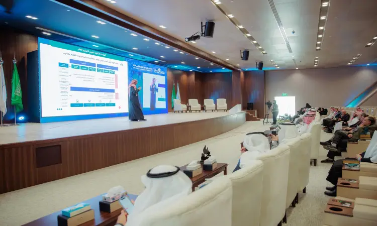 يُقصد كلمته على المسرح امام شاشة كبيرة تعرض بياناً ونصوصاً باللغة العربية ضمن فعاليات "الملتقى واحد"، وذلك لحضور جمهور يرتدي الشماغ السعودي، والعقال، وبشت السعودي، والغترة السعودية. ويتسع هذا في قاعة المؤتمرات الحديثة خلال يوم التعليم العالمي 2024، باستثناء جامعة القصيم.