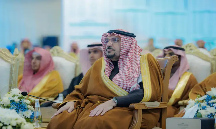 رجل يقف ويرتدي سعوديةقالًا وبشتًا سعوديًا فوق شماعه، ممثلًا لإمارة القصيم، على كرسي فخم خلال فترة التوعية الثقافية والتثقيفية. وتزين أمامها التنسيقات التنسيقية وزجاجات المياه في الاعتبار الاعتبارية الرسمية المقام في رحاب جامعة القصيم.