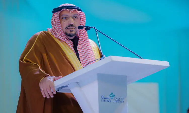 رجل يلقي يرتدي الغترة السعودية والشماع والعقال والبشت السعودي العادي كلمة من على منصة بيضاء تحمل شعار جامعة القصيم، وذلك أمام خلفية زرقاء، وفتحة موضوعات توعية وصحة وتثقيف، ومبرزًا دور إمارة القصيم في تحقيق التوازن التنموي.