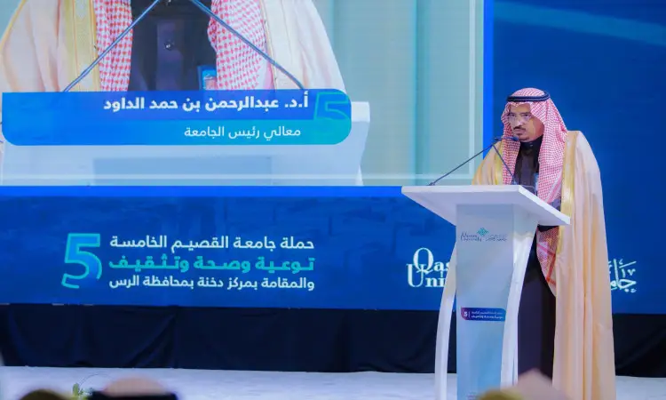 الرجل المرتدي الغترة والعقال والبشت السعودي جاكسوناً من على منصة بميكروفون. خذ خلفه شاشة كبيرة تعرض صوره ونصوصاً باللغة العربية. ويأتي هذا الأمر فقط من جامعة القصيم، مسلطاً الضوء على جهود إمارة القصيم في تحقيق يقظة التنموي والوعي والوعي في المجتمع.
