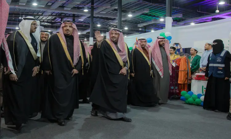 يسير مجموعة من الرجال تولى الغترة السعودية أو الشماغ والعقال، ويضع الشركاء البشت السعودي، يتقدمهم أمير منطقة القصيم، في أروقة المقامة داخل الجامعة ضمن مهرجان الجامعة. في الجانب الآخر من الممر عدد من المعجبين، بينما تزين المكان بالونات ملونة وعروض تتجسد تراث الشعوب في الخلفية.