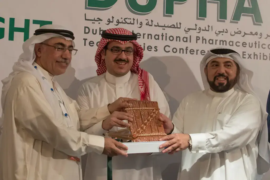 القطة ثلاثة رجال مرتدين الغترة أو الشماغ السعودي والعقال والبشت السعودي بابتسامة، وبالتالي فإن نتيجة مؤكدة أمام مؤتمر دبي الدولي للصيدلة، ممثلين كلية الصيدلة في جامعة القصيم.