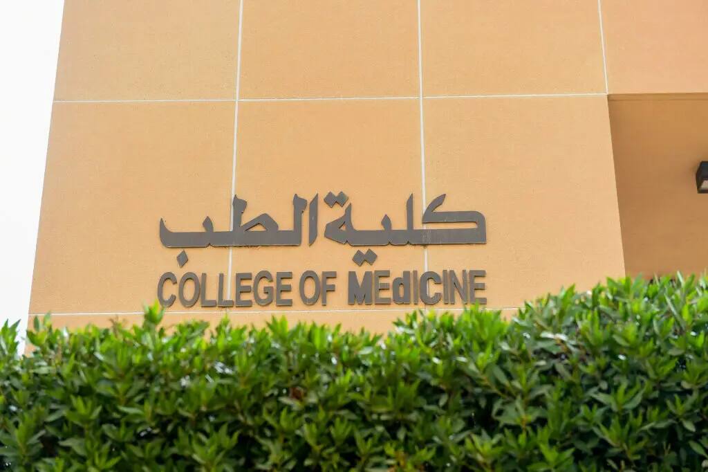 تحف على جدار مبنى أبيض اللون لوحة تحمل اسم "كلية الطب" في القصيم باللغتين العربية والإنجليزية، ويعلوها نص "كلية الطب جامعة القصيم"، وتخفيها جزئيًا الشجيرات الخضراء في الخليج. و بوجود حول المبنى الطلابي وأعضاء الجسم تعين غترة أو شماغاً وقاعدة مع البشت السعودي الأصلي، فيثبات الأصالة السعودية. وقد أصبح هذا المبنى مركزًا هامًا لعقد الهيئة الهيئة السعودية منذ عام 2016.