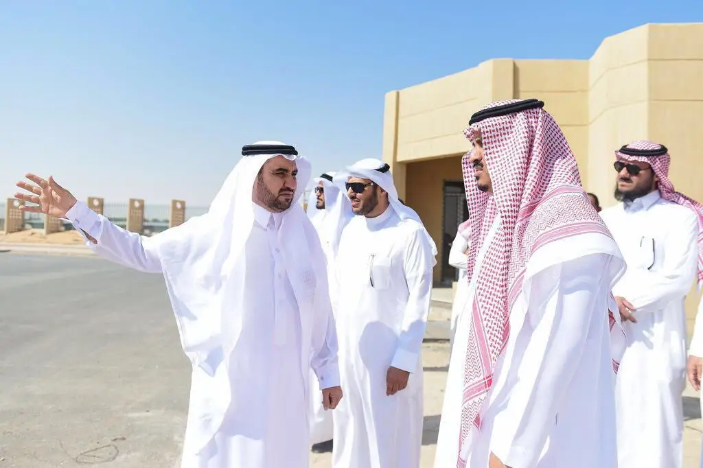 الاتصال مجموعة من الرجال مرتدين الغترة أو الشماغ السعودي مع العقال والبشت السعودي في مكان تحت المجهر الشمس القريبة من مجمع كليات عنيزة لجامعة القصيم. ويظهر بوضوح وهو يشير إليه خلال العصر الحديث، فيما يتعلق بتذوق الباقون باهتمام، حيث يناقشون منشآت الكليات بجوار مبنى لون رملي تحت سماء صافية.
