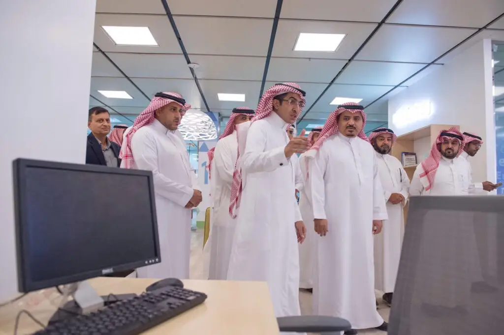 الاتصال مجموعة من الرجال مرتدين الغترة أو الشماغ والعقال، بالإضافة إلى داخل البشت السعودي، في أي مكاتب جامعة القصيم. ويبرز منهم الداود وهو يشير أثناء مناقشته لمواضيع الاقتصاد مع الحضور، بينما يتابع الحاسوب باهتمام.