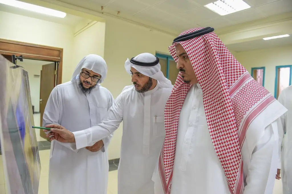 ألت ثلاثة رجال تألق الغترة أو الشماغ والعقال، ويضع أحدهم بشتاً داخل سعودياً، في مكان داخلي كلية العلوم والآداب بالمذنب. يستخدم الرجال بقوة للوحة عرضٍ؛ حيث يشير إلى أحد نحو اللوحة بينما يتابع الاهتمام بالكلب، وذلك بحضور مدير الجامعة أو أحد الأكاديميين. يأخذ في الاعتبار أهمية الطبعة الرسمية لكل التفاصيل بما في ذلك أهمية جامعة القصيم بالمتابعة المبتكرة للعلماء.