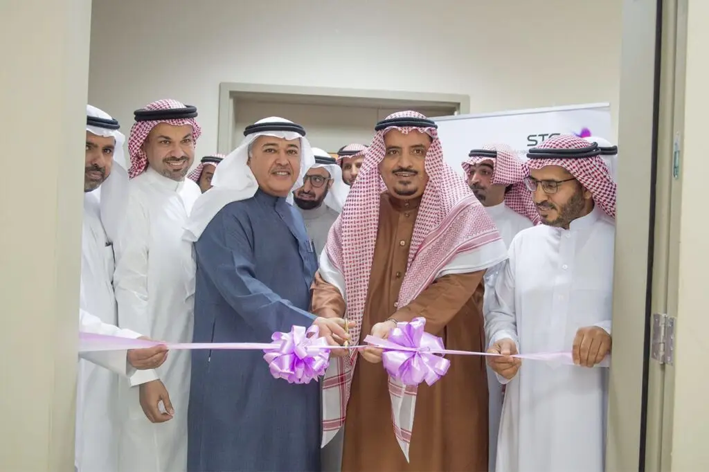 مجموعة من الرجال الحاضرين الغترة أو الشماغ السعودي مع العقال والبشتت السعودي الاتصالون عند مدخل معمل STC في كلية الفنون في القصيم، التفاعلي حيث بقص شريط وردي إيذانًا بافتتاح المعمل. وتبعث الابتسامات على وجوه تعبيرين قوية، وذلك بحضور ورعاية شركة الاتصالات السعودية.