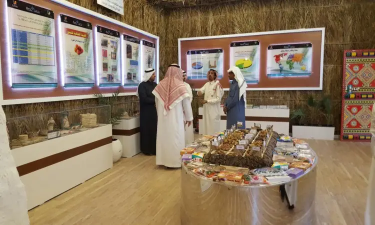 للاتصال عدد من الرجال مرتدين الغترة أو الشماغ والعقال، وبعضهم يرتدون البشت السعودي، وهم يتحاورون داخل قاعة العرض في مهرجان الجنادرية. ستيفن بهم ملصقات وسلال منسوجة وطاولة عرض كونيتيكت التمور والأطعمة المعلبة. وتتميز المكان بجدار مميز من سسف النخيل وأرضية خشبية، في نظام يعكس الطابع التراثي للفعالية التي تشارك بها جامعة القصيم.