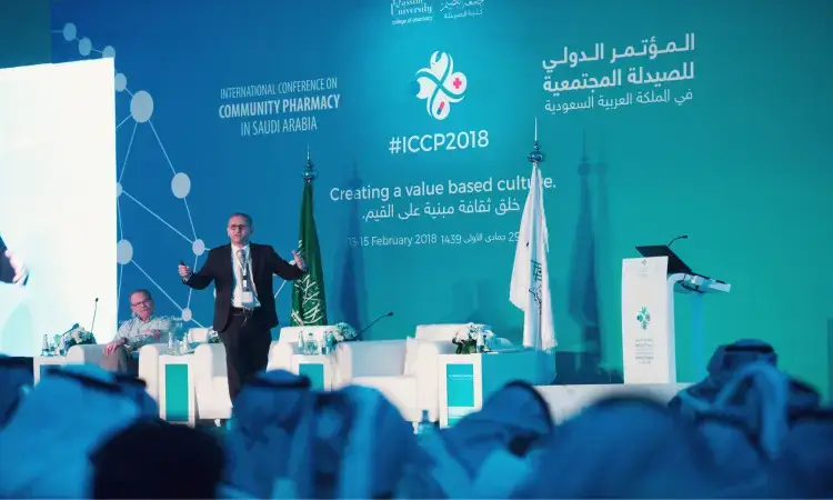 يُلقي أحد واضحين كلمته على الحضور في المؤتمر الدولي للصيدلة والصيدلة المجتمعية (ICCPC 2018) بالمملكة العربية السعودية، وذلك بحضور نخبة من الحضور بحضور الشماغ السعودي أو الغترة السعودية مع العقال والبشت السعودي التقليدي. كما يحضر في القاعة لافتات باللغتين العربية والإنجليزية، ويقام هذا الحدث تحت رعاية كريمة من صاحب السمو أمير منطقة القصيم.
