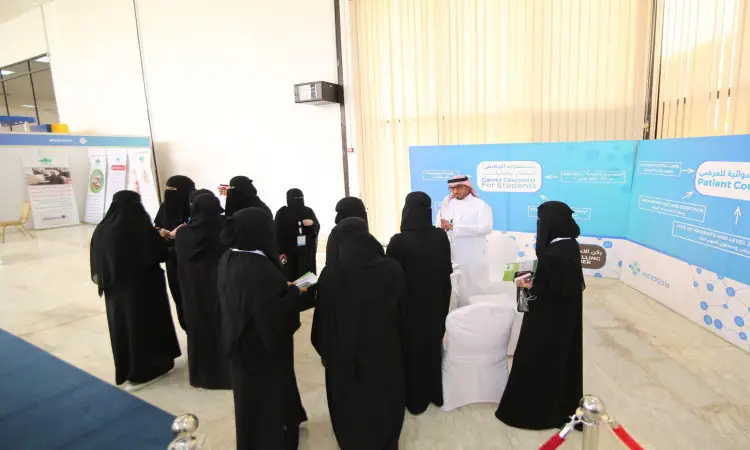 مجموعة من ارتداءن عبايات سوداء ونقاباً تتن في نصف دائرة حول رجل ارتدى ثوباً أبيض مع غترة سعودية وقال وبشت سعودي، وذلك عند إحدى الأجنحة خلال فعاليات المؤتمر الدولي للصيدلة، حيث اشتراكهم الإنارة الساطعة ولافتات تعريفية معلقة على الجدران، في إطار منظمة احترام الفنان الرسمي لجامعة القصيم.