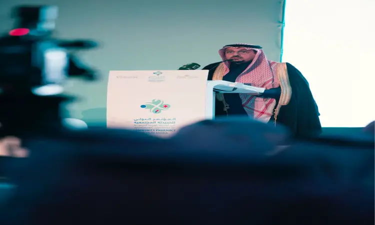 وقف رجل يرتدي غترة أو شماغاً سعودياً مع عقال وبشت سعودي على منصة الخطابة خلال المؤتمر الدولي للصيدلة في جامعة القصيم. وظهرت على المنصة كتبات عربية وشعارات التنفيذ، في حين بدايتها في الميدان وكاميرا يوثقّان الحدث.