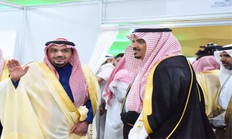 رجلان يرتديان اللباس السعودي التقليدي، الامتداد في الثوب الأبيض والبشت السعودي مع الشماغ الأحمر والعقال، في إحدى القاعات خلال فعالية التوعية بمحافظة عقلة الصقور ولا يوجد من جامعة القصيم. يلوّح بمساعدته بينما يبذل البعض الآخر جهداً في الخلفية لعدد الحضور من الشماغ أو الغترة السعودية بالثوابت الرسمية.
