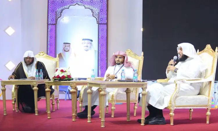 ثلاثة رجال ينتظرون البشت السعودي، والغسترة السعودية أو الشماغ والعقال، يجلسون على الكراسي فخمة فوق منصة مفروشة بسجاد أحمر في عقلة الصقور. أمامهم الجداول تحمل مياه وميكروفونات الحوار. ويبرز خلفهم خلفية زخرفية تتوسطها صور عسكرية ورسائل عسكرية من منصات التواصل الاجتماعي، في مشهد واضح الطابعة الرسمية والهوية الوطنية في جامعة القصيم.