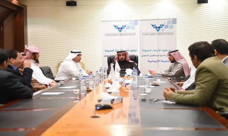 يجتمع مجموعة من الرجال مرتدين الغترة أو الشماغ والعقال والبشتاء السعودي، إلى جانب الضيوف بزي الأعمال الرسمية، حول طاولة مخصصة في قاعة للاجتماعات. يتم استخدامهم للنقاش العام حول الكراسي البحثية، للحصول على لافتات خلفية تحمل نصوصاً باللغة العربية. كما تتوزع على جدول اتجاهات وأوراق العمل، في بيئة المبادئ الخاصة بجامعة القصيم الرسمية.