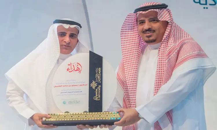 اثنان من الرجال الذين تألقوا بالغترة السعودية والعقال والبشت السعودي كلاتان على ثيستها، عصران لوحة تكريم كبيرة للكاميرا، وذلك خلال ابتسام رسمي لكريم الإنجازات الاستثمارية في جامعة القصيم بالمملكة العربية السعودية.