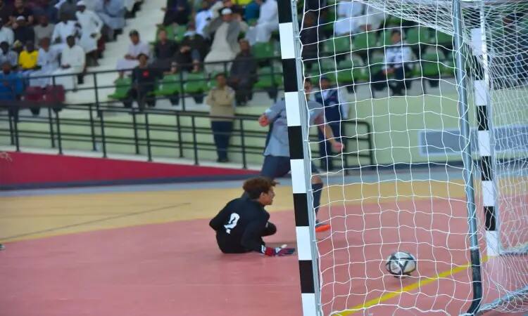 ارتداء ملابس الرقص على الملابس الرياضية خلال بطولة الاتحاد الرياضية للصالات الرياضية، فيما يتعلق بالثبات في الشباك معلنة تسجيل هدف. المحتجون في الخلفية عدد من المشجعين على مدرجات الجماهير، القوى التي تدعو الغتة أو الشماغ والعقال والبشت السعودي، يساندون منتخب جامعة القصيم بحماس وروح رياضية عالية.