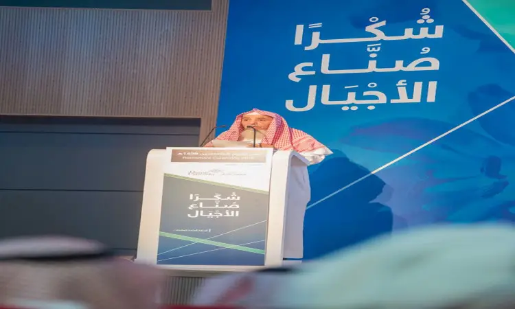 رجل مرتدياً الغترة السعودية والعقال والبشت السعودي على المنصة، مشهوراً خلال المتقاعدين في جامعة القصيم. كوك خلفه الزرقاء الكبيرة تحمل نصوصاً عربية وشعار الجامعة، بينما تظهر بعض الحضورين في الصفوف التأسيسية.