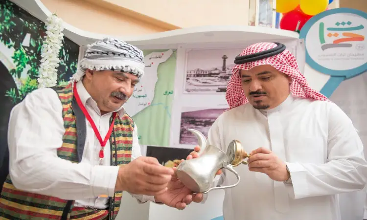 في مهرجان تراث الشعوب، ويشكل رجلان ودعا الغترة والعقال والبشت السعودي، بينما ارتدى الشماغ السعودي والقال، القهوة العربية من دلّة معدنية في ركن ثقافي. لتظهر في الخلفية خرائط وصور وبلونات بالإضافة إلى إعلان عن مسابقة القرآن والسنة ومكافآت مخصصة للفائزين.