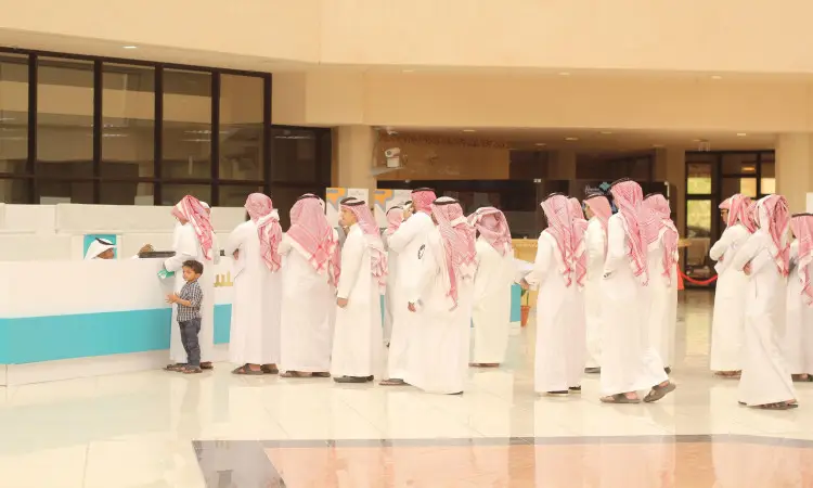 الاتصال مجموعة من الرجال مرتدين الثياب البيضاء والبشت السعودي، ويضعون الشماغ أو الغترة السعودية مع العقال، مصطفين داخل القاعات خلال فعاليات يوم المهنة في جامعة القصيم. وبجوارهم فتى صغير إلى جانب طاولة الاستقبال، وهو طائر للأعلى باهتمام.