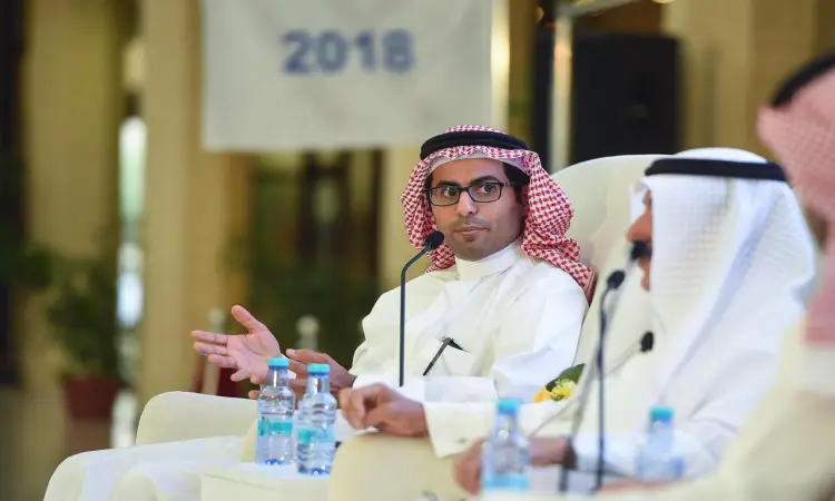 خلال يوم المهنة في جامعة القصيم، يظهر رجل مرتدياً الغترة السعودية، الشماع، والعقال فوق البشت السعودي وهو غالباً بحماس في إحدى الجلسات الرسمية، مستخدماً بيديه بينما يتوجه إليه شخصان إلى الجانب. تتوزع اجتماعيا على طاولة المجتمع وخلفياتهم وتحمل شعار عام 2018.