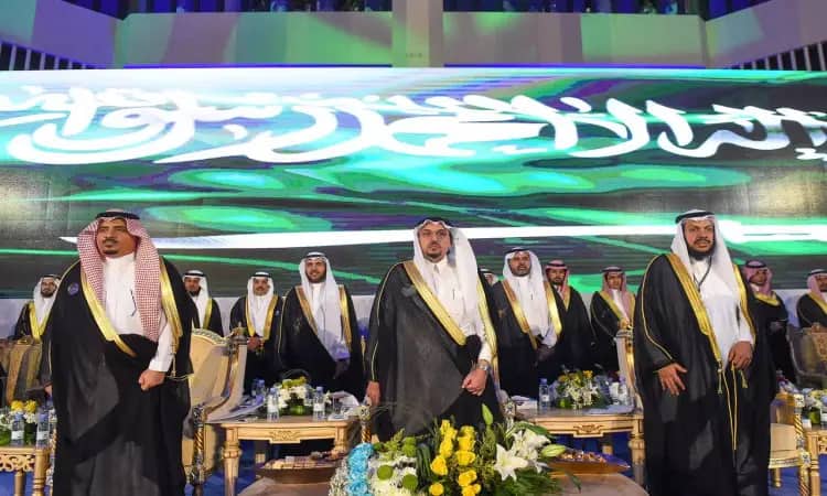 الاتصال كبير من الرجال مرتدين الغترة أو الشماغ السعودي مع العقال والبشت السعودي، بينهم خريجو جامعة القصيم لتخرجهم على منصةٍ مزينة بالورود وتزيينات الزهور، وخلفهم عرض مُضيء لنص عربي وشعار المملكة العربية السعودية الخلفية والعلم السعودي، ومراقبة في أيضا صورة سمو أمير منطقة القصيم.