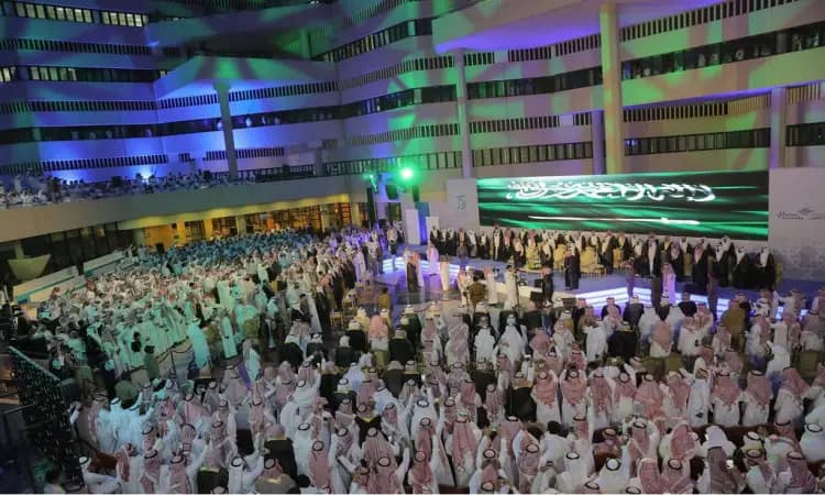 حشد كبير من الأشخاص مرتدين الشماغ السعودي أو الغترة والعقال والبشت السعودي في ساحة خارجية حديثة الطوابق، ازدانت بالأضواء ملونة وشاشة كبيرة تعرض نصوصاً باللغة العربية، قوة بتخريج دفعة من خريجي جامعة القصيم.