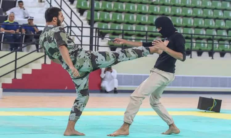 Dressed in a camouflage outfit, wearing a Saudi bisht and a headband, a person wearing a Saudi bisht and a headband wielded a knife during a martial arts demonstration organized by the College of Education in a gymnasium in the presence of a number of spectators. The series of Saudi bisht chains added to the atmosphere of Qassim University and its academic events.