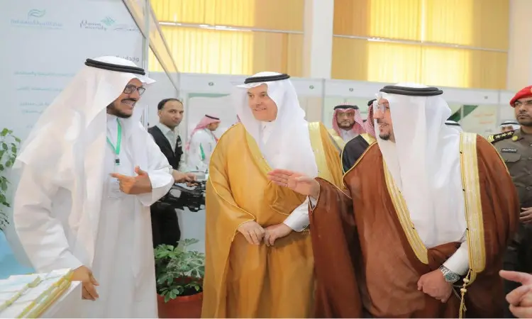 يتبادل مجموعة من الرجال مرتدين الغترة أو الشماغ والعقال، ومُرتدين البشت السعودي، أطراف الحديث ويوجهون الخيمات خلال أُقيمت في مدينة بريدة، حيث يناقشون فرص الاستثمار الزراعية الزراعية. يشارك أحد بالإشارة بيده بينما يصغي الباقون باهتمام، ويشترك في التأمين في الخلفية على النظام.