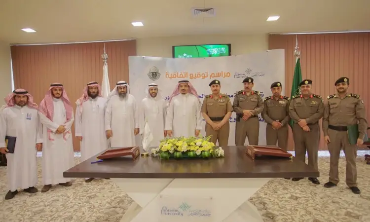 A group of men wearing the Saudi ghutra or shemagh and aqal, some in formal Saudi winter, along with a number of security men in their uniforms, are pictured behind a work table with documents and flowers on it. They all sat in front of a board with text in Arabic, as part of an event held at a driving school for women in Qassim.