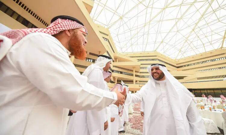 في حفل استقبال رسمي لعيد الفطر (عيد المعايدة) أُقيم داخل جامعة القصيم، شوهد عدد من الرجال يرتدون الزي السعودي التقليدي، بما في ذلك الغترة والشماغ مع العقال، ويتميّزون بالبشت السعودي، وهم يتبادلون المصافحة. يتميز المكان بسقف زجاجي، وتظهر في الخلفية طاولات مستديرة أنيقة مُعدّة خصيصًا لهذه المناسبة.