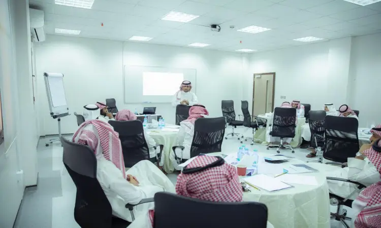 يجتمع مجموعة من البارزين والعلماء الحاضرين الغترة أو الشماغ والعقال والبشت السعودي التقليدي في قاعة مؤتمرات حديثة ومضاءة بشكل جيد في جامعة القصيم، وذلك للمشاركة في برنامج تطوير المؤتمر والاستماع إلى المؤتمر الرسمي. وتوجد على طاولات العرض التقديمي وقوارير المياه المتعددة للحضور.