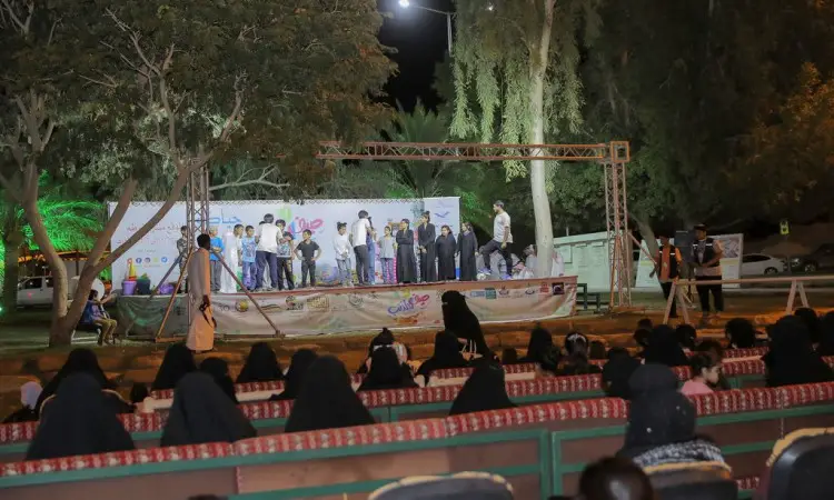 لمهرجان صيف المذنب في الهواء الطلق ليلاً، حيث اجتمعت الحضور على مسرح مجلس النواب مضاء، بينما حضرت جلسة جمهور من الرجال الحاضرين الغترة أو الشماغ والعقال والبشت السعودي، هوليوود من مقاعد النساء بعباءاتهن السوداء، على مواجهة للمسرح. بدت الأعمال الفنية والزينة واللافتات في الخلفية لتجسد جامعة القصيم الجديدة وما تتميز به من تميز.