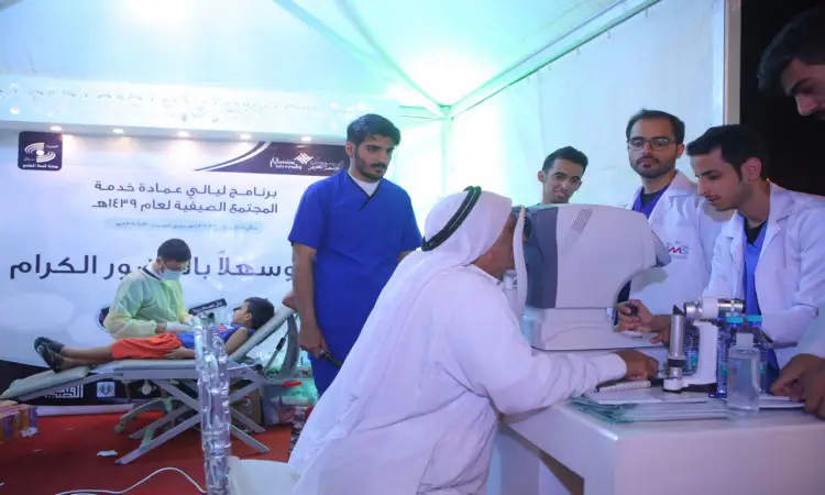 يقوم أحد الممارسين الصحيين بمساعدة مستفيد مسن أثناء إجراء للعين باستخدام جهاز مخصص داخل المستشفى الطبي، وذلك ضمن نظم صحية صحية جامعة القصيم لخدمة، حيث يظهر في مشهد عدد من الكوادر الطبية مرتدين الغترة أو الشماغ والعقال والبشت السعودي، بالإضافة إلى وجود أحد المرضى المستلقين على السرير الطبي، في مشهد يجسد الكفاءات الجامعية بالتوعية الصحية المجتمعية.