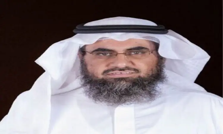 رجلٌ ذو لحيةٍ كثيفة ونظارة، يرتدي ثوبًا أبيض تقليديًا، بغترة بيضاء مثبتة بعناية بعقال أسود، ويرتدي بشتًا سعوديًا أنيقًا، يقف على خلفية داكنة. يجسد حضوره المهيب ووقفته الرصينة المسؤولية والقيادة اللتين تليقان بمنصب مدير جامعة القصيم.